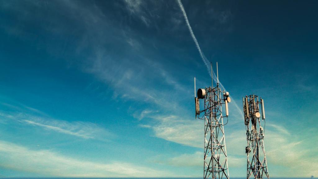 Two cell phone towers in front of a blue sky